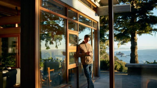 person on phone leaning against outside wall with scenic view at airbnb rental property